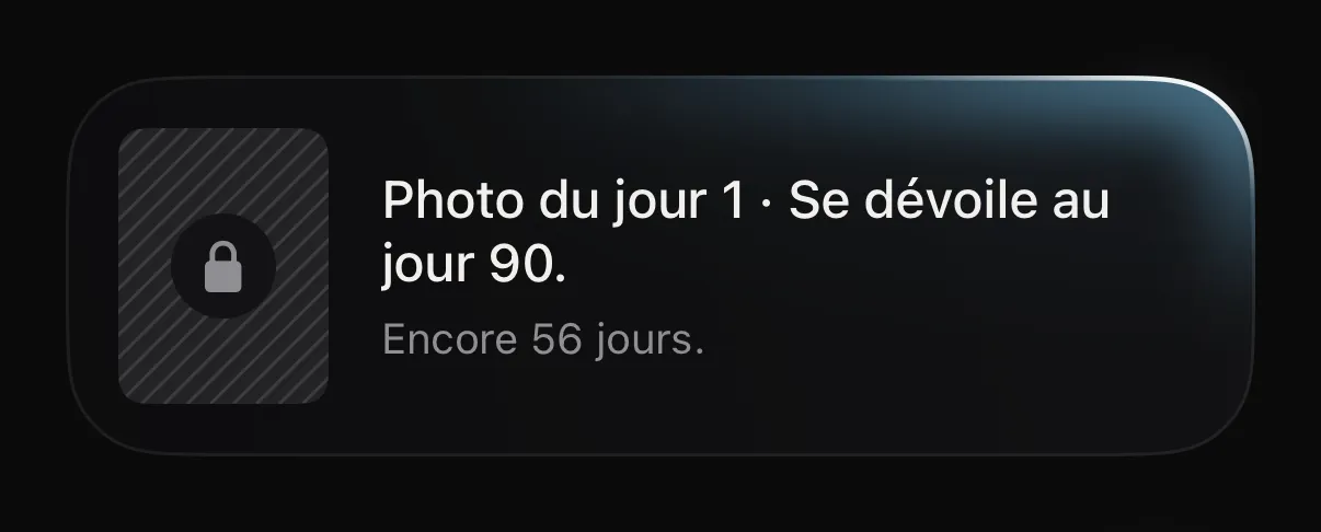 Carte de l’app : « Photo du jour 1. Se dévoile au jour 90. Encore 21 jours. », avec un cadenas.